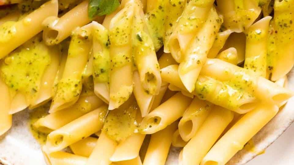 Penne pasta with creamy pesto sauce on a plate.