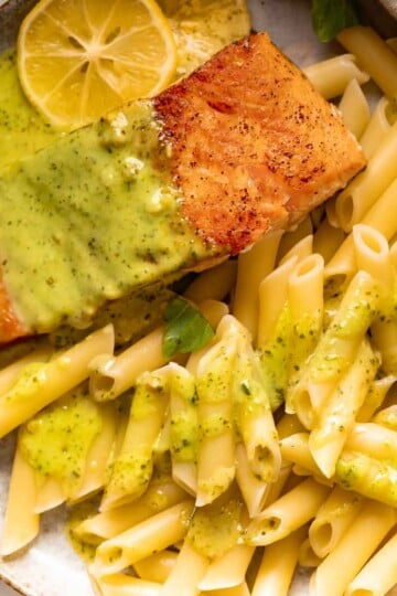 Salmon and pesto pasta served with penne pasta flavored with pesto on a plate.