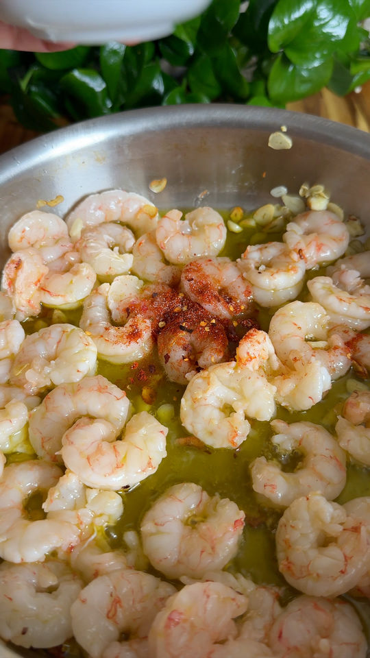 Shrimp cooking in a pan with garlic and spices.