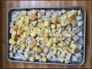 Cubed bread and cornbread mix on a baking sheet, ideal for stuffing preparation.