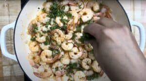 Cooking garlic butter shrimp in a skillet topped with fresh parsley for a delicious seafood dish.
