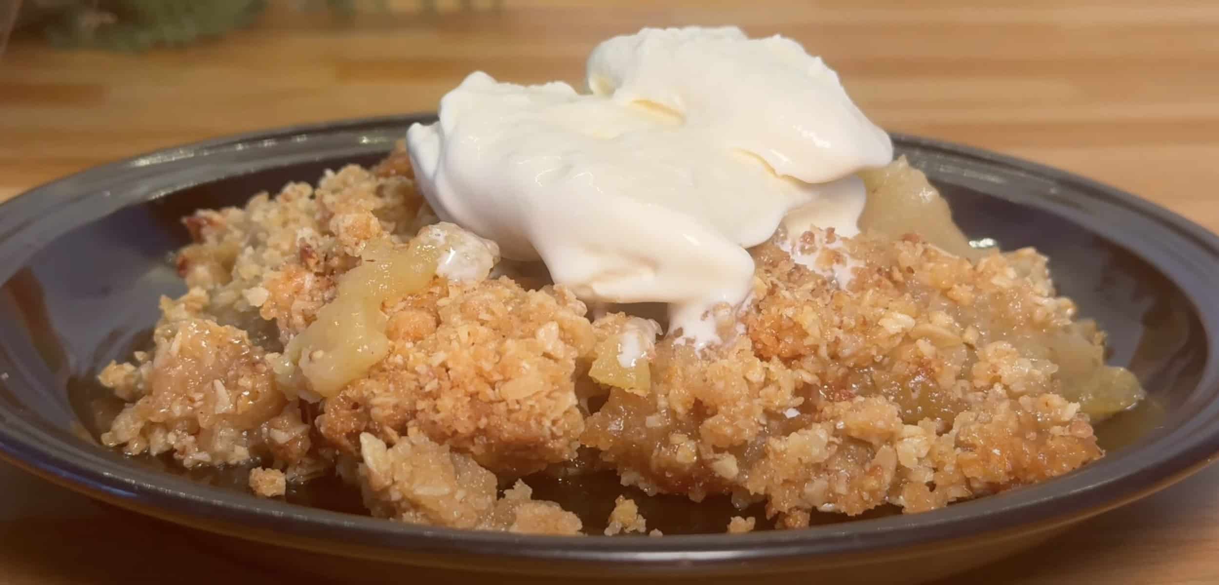 Homemade apple crumble with ice cream on a plate, showcasing a delicious dessert with a crunchy topping.