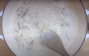 Creamy sauce with herbs being stirred in a pan, perfect for pasta or chicken dishes. Cooking close-up.