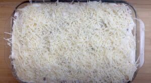 Glass baking dish filled with shredded cheese, ready for oven baking. Perfect for casseroles or lasagna recipes.