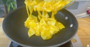 Cooking scrambled eggs in a nonstick pan, focusing on vibrant yellow and cooking technique.