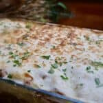 Delicious homemade baked lasagna topped with cheese and fresh herbs in a glass dish.