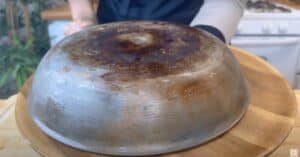 Upside-down metal bowl on wooden surface in kitchen setting.