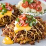 Cheesy taco casserole topped with tomatoes and cilantro, served with mashed potatoes garnished with sliced tomatoes.