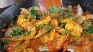 Spicy shrimp cooking in a skillet with fresh herbs and vibrant sauce. Ideal for seafood lovers.