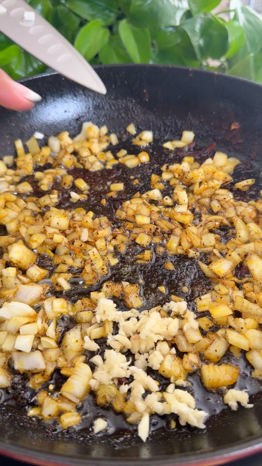 Chopped onions and garlic sautéing in a skillet.