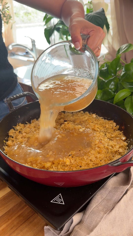 Pouring liquid from a measuring cup into a skillet.