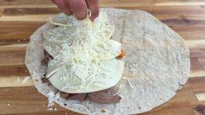 Preparing a quesadilla with sliced cheese and grated cheese on tortilla.