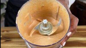 Creamy sauce in a blender. Perfect for dips, dressings, or marinades. Vibrant orange hue. Ready to serve.