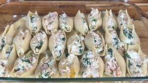 Stuffed pasta shells with ricotta, spinach, and chicken in a glass baking dish, ready for baking.