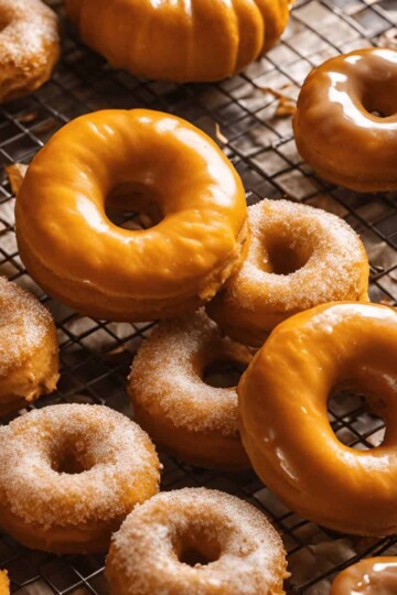 Glazed and sugar-coated donuts on a cooling rack, showcasing a delicious variety of flavors for dessert lovers.