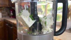 Feta cheese and herbs in a food processor for a creamy dip.