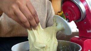 Mixing bread dough with a stand mixer; hand stretching dough for texture check.