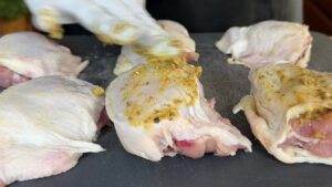 Marinating chicken thighs with spices on cutting board for flavorful cooking.