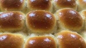 Golden, freshly baked dinner rolls with a glossy finish, arranged closely together. Perfect for bread lovers.