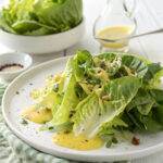 Fresh Caesar salad with romaine lettuce, creamy dressing, and parmesan cheese on a white plate.