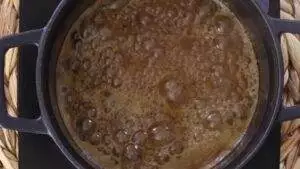 Boiling caramel in a black pot, creating a rich and bubbly texture for a delicious dessert topping.