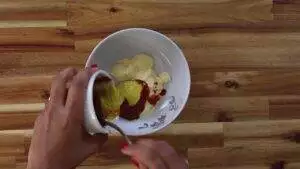 Mixing sauces in a white bowl on a wooden table for a flavorful dressing recipe.