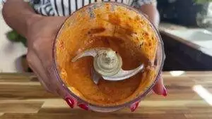 Fresh homemade marinate in a container held by hands on a wooden counter.