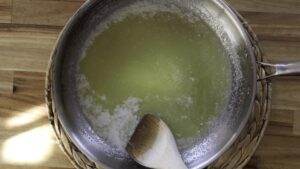 Melting butter in a pan with wooden spoon on a woven mat background.