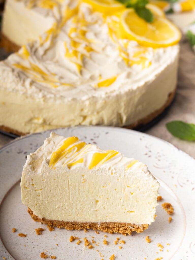 Slice of no-bake lemon mascarpone cheesecake on a plate, with a creamy topping and lemon zest accents.