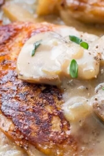 Pan-seared chicken breast with creamy mushroom sauce topped with herbs.
