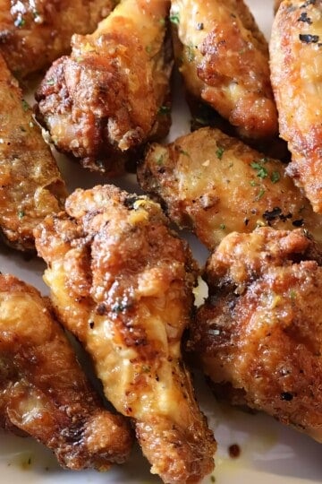 Crispy golden-brown chicken wings garnished with herbs, perfect for a delicious appetizer or party snack.