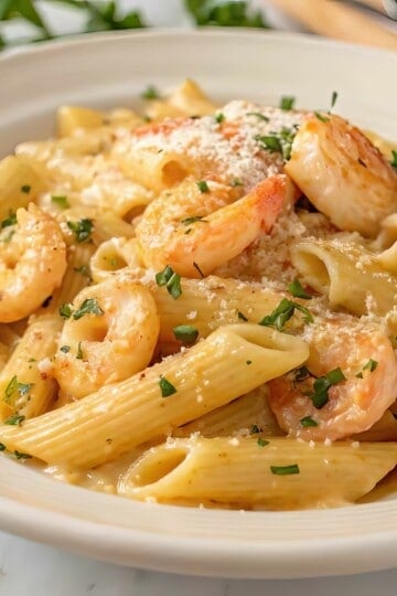 Creamy shrimp pasta topped with Parmesan and parsley on a white plate, perfect for a delicious Italian dinner.