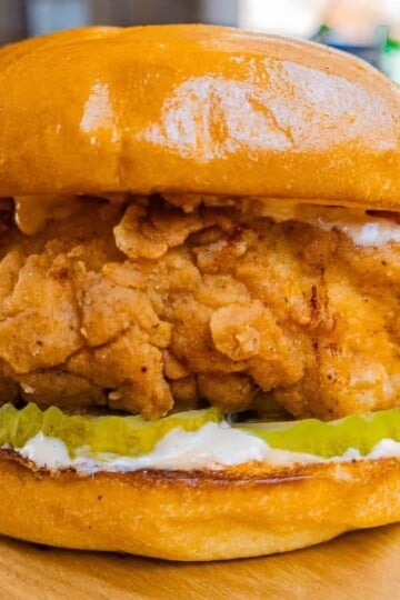 Crispy fried chicken sandwich with pickles on a golden bun, showcasing delicious savory flavors.