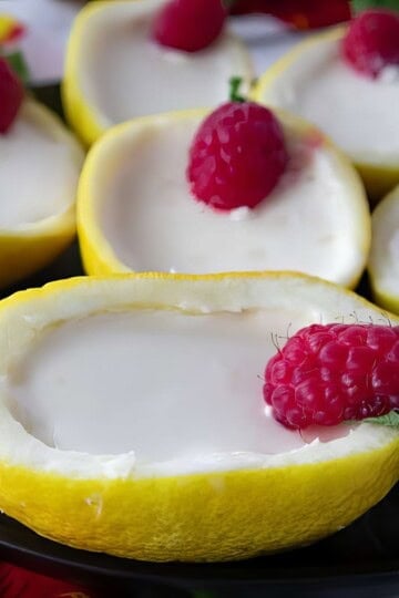 Creamy lemon sorbet served in lemon halves, garnished with fresh raspberries and mint leaves.