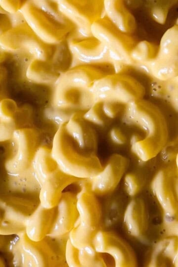 Creamy macaroni and cheese close-up with rich, golden sauce coating elbow pasta. Perfect comfort food dish.