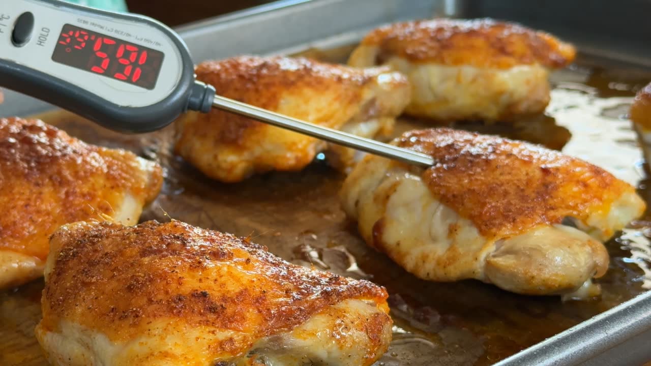 Roasted chicken thighs with crispy skin on baking sheet, thermometer shows 165°F.