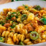 Delicious spirali pasta with olives, chicken, herbs, and spices in a white bowl, perfect for a savory meal.