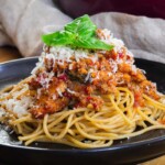 Spaghetti with rich hidden veggie pasta sauce topped with fresh basil and grated cheese on a black plate.