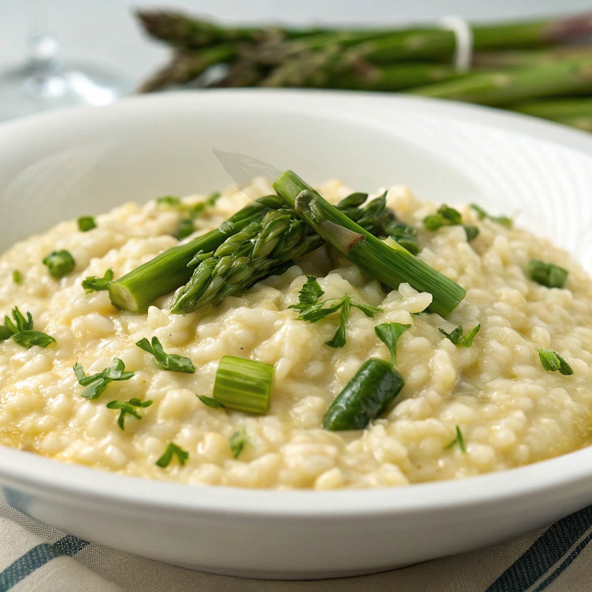 Risotto agli Asparagi (Asparagus Risotto) topped with fresh herbs served in a white bowl, perfect for a gourmet meal.