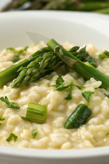 Creamy Risotto agli Asparagi (Asparagus Risotto) garnished with fresh parsley in a white bowl.