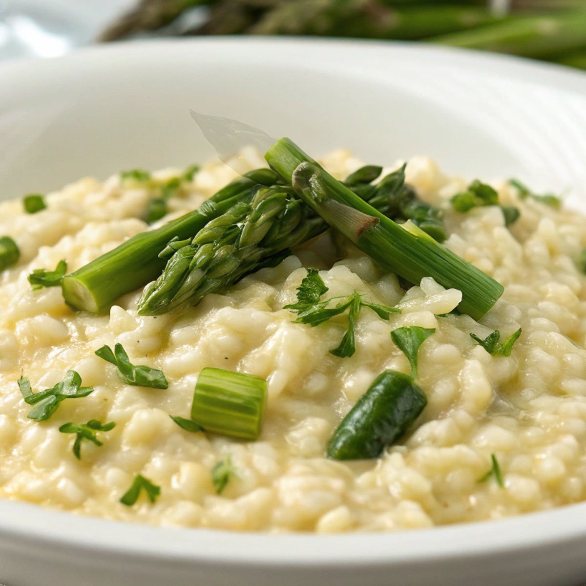 Creamy Risotto agli Asparagi (Asparagus Risotto) garnished with fresh parsley in a white bowl.