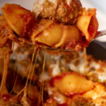 Cheesy baked meatball pasta in tomato sauce on a fork.