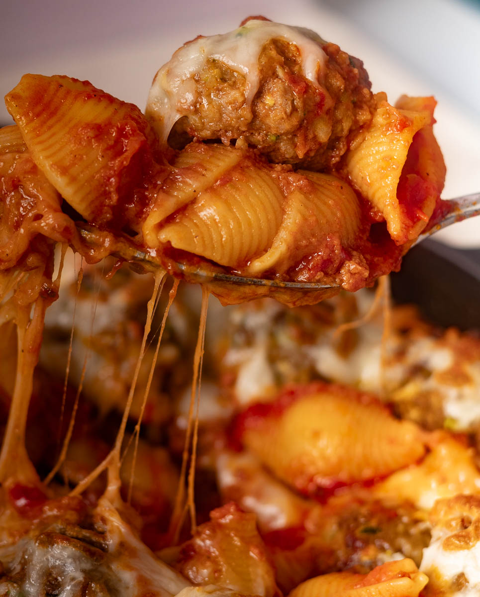 Cheesy baked meatball pasta in tomato sauce on a fork.