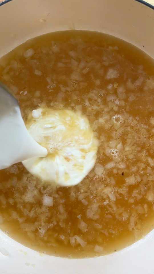 Adding cream in pot of liquids and diced onions.