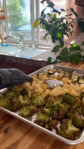 Tray of roasted vegetables, broccoli, zucchini, and potatoes on a kitchen counter.