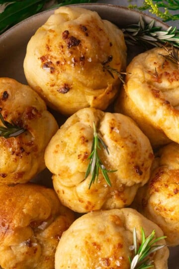 Focaccia muffins topped with rosemary in a bowl.