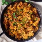 Bowl of savory Chicken chorizo and stuffing casserole with herbs and cranberries.