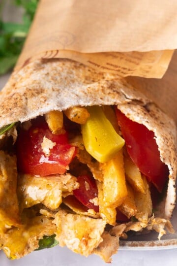 Viral doner kebab with grilled chicken, bell peppers, and lettuce on a plate with roasted peppers.