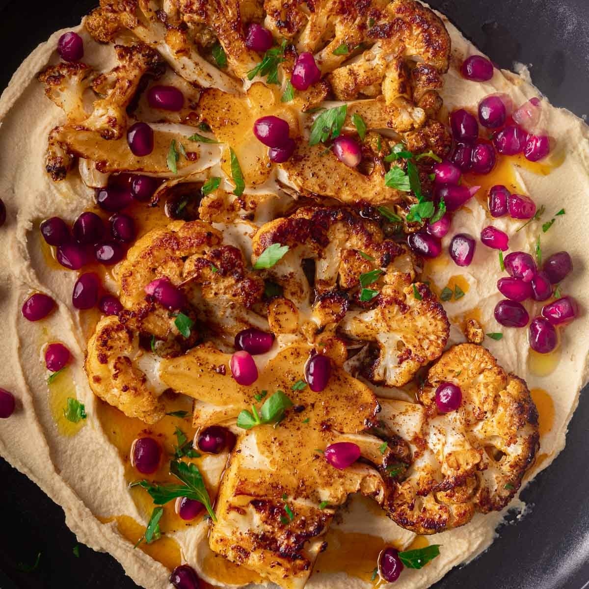 Roasted cauliflower steaks on a bed of hummus