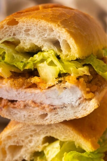 Baked chicken caesar sandwich with lettuce on a fresh baguette, close-up view.